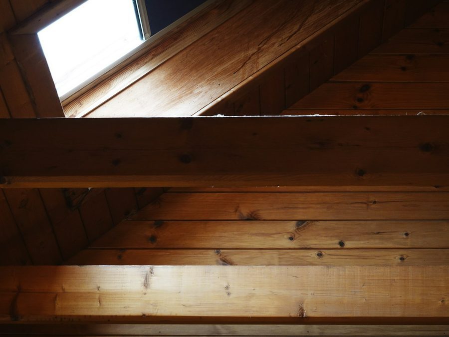 Dachfenster in einer Holzverkleidung unter der Dachschräge, Licht fällt auf die Balken