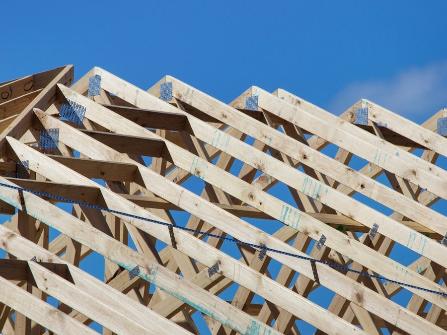 Neuer Dachstuhl aus hellem Holz mit vielen Bindern vor blauem Himmel