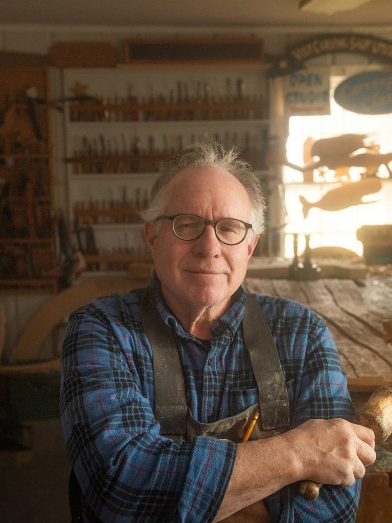Portrait von Georg Stangl, Dachdeckermeister, mit Brille, kariertem Hemd und Latzhose in der Werkstatt
